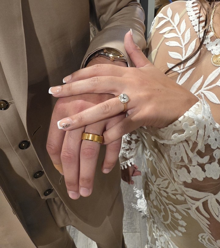 Criativo de anúncio no Facebook da The Ridge: as mãos de um casal em um casamento, a aliança dourada escovada dele sobre o anel de noivado dela