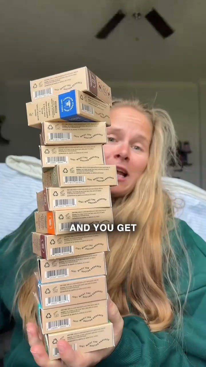 Criativo de anúncio em vídeo no Facebook da Dr. Squatch: uma mulher segura uma pilha alta de caixas de sabonete, com a legenda And You Get